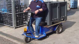 Tractor electrico hombre a bordo JACK L transportando un contenedor pl&aacute;tico