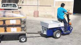 Tractor electrico para almacenes JACK MASTER con un remolque en una calle